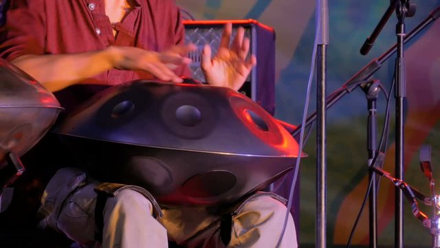 Man playing tank drum or hang on stage of ethnic open air concert. Relaxation, folk, meditative and traditional ethnic music concept