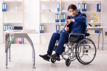 Young male employee in wheelchair working in the office 