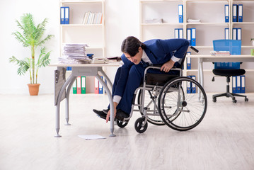 Young male employee in wheelchair working in the office 
