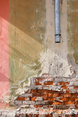 grunge shabby brick wall with plumbing pipe. vertical view