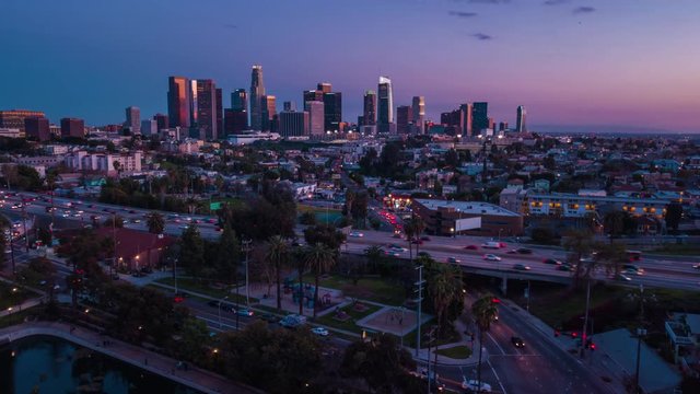 Cinematic aerial time lapse view of skyscrapers of Downtown, Echo park lake and 101 freeway traffic at dusk