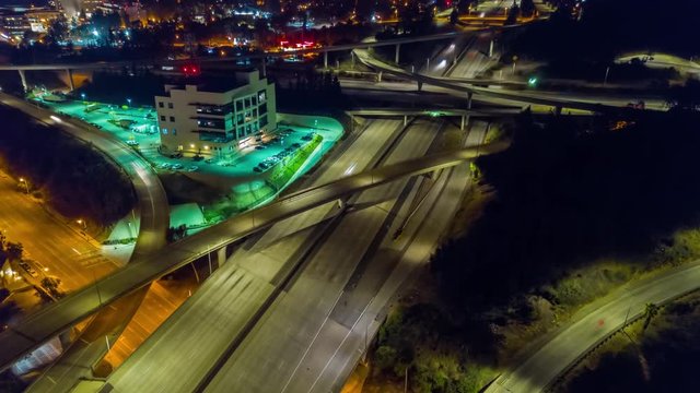 Urban aerial drone time lapse in motion or hyperlapse at night flying towards a LA interstate with traffic showing the on and off ramp indicative of the fast paced futuristic city lifestyle