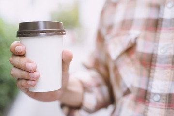 business man hand holding paper cup of take away drinking coffee  on natural morning sunlight. space Place for your text or logo.