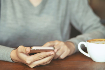 female lady using on cell telephone during rest in coffee shop. hipster girl sitting in watching message on mobile phone during drink coffee break.