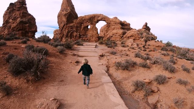 Young Child Running on Path to Desert Red Rock Arch Formations