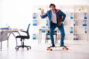 Young handsome businessman with longboard in the office 