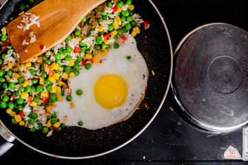 Fried frozen vegetable with rice and fried egg. Food remains in a black frying pan