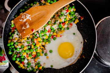 Fried frozen vegetable with rice and fried egg. Food remains in a black frying pan