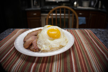 Rice and ham topped with two eggs plate lunch in an empty kitchen on the table