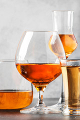 Set of hard strong alcoholic drinks and spirits in glasses in assortment: vodka, cognac, tequila, brandy and whiskey, grappa, liqueur, vermouth, tincture, rum. Gray bar counter 