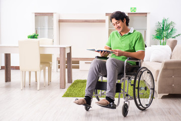 Young handsome man in wheelchair at home 