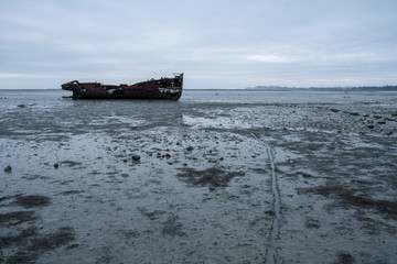 Rusty old ship wrech lying on the mud flats at Port Motueka