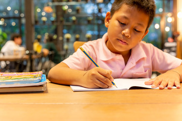 asian schoolboy hand with pencil doing his homework at home.