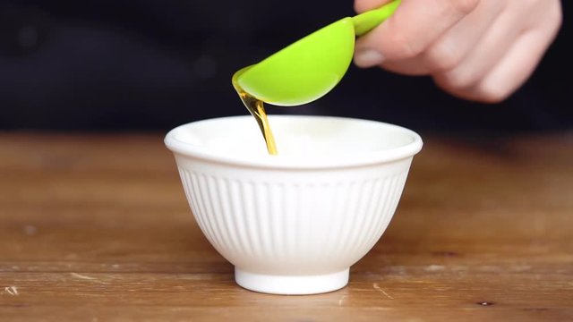 Step by step. Measuring olive oil with a tablespoon.