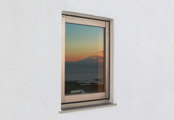 ホテルの白壁の窓に映る富士山の夕焼け空