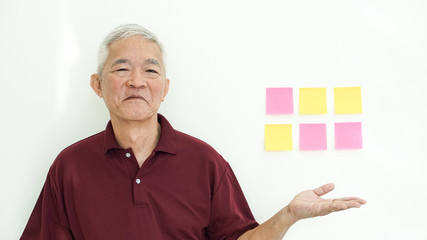 Handsome Asian senior man presenting white copy space