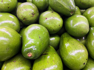 Spectacular detail of green avocados in perfect condition, stacked in the supermarket.