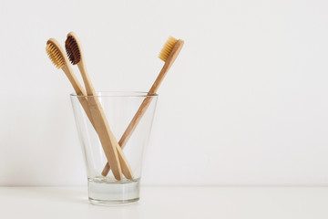 set of natural toothbrushes in glass on table in bathroom