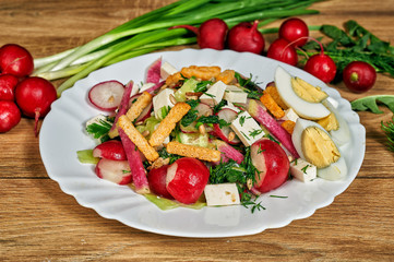 Spring salad in a bowl with radish , herbs , egg and cheese