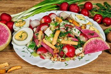 Spring salad in a bowl with radish , herbs , egg and cheese