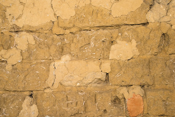 Adobe brick wall with worn-off plaster