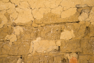 Adobe brick wall with worn-off plaster