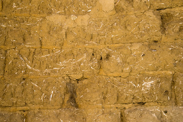 Adobe brick wall with worn-off plaster