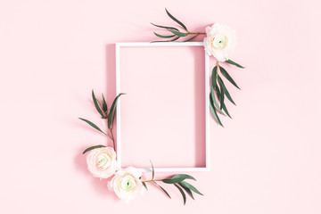 Flowers composition. White flowers, eucalyptus leaves, photo frame on pastel pink background. Flat...