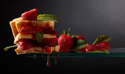 Belgian waffles with strawberries and honey garnished with fresh mint.