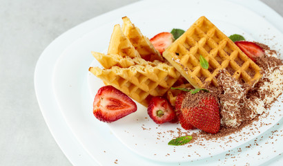 Belgian waffles with strawberries and cream, mint and chocolate chips.