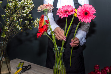 Female florist making a bouquet of gerberas in a flower shop
