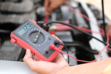 auto mechanic check car battery voltage by voltmeter multimeter - obrazy, fototapety, plakaty