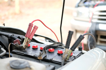 mechanic use jumper cables to charge dead car battery