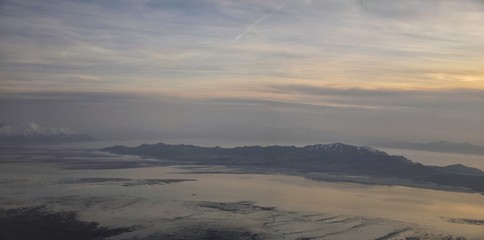 Aerial view from airplane of Antelope Island at sunset, view from Magna, sweeping cloudscape at sunrise with the Great Salt Lake State Park in winter. USA, Utah.