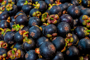 Fresh mangosteen for sale at an outdoor market. Mangosteen piles in one frame. Mangosteen is an Indonesian fruit that has purple skin. Many mangosteen to sell at the markets.