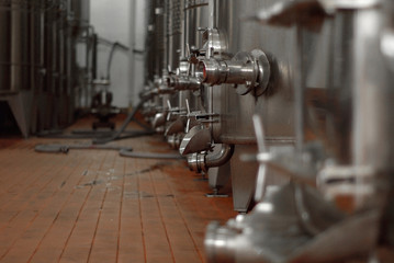 Fototapeta na wymiar Premises of the winemaking factory. Metal parts of the equipment. Large metal barrels for wine.