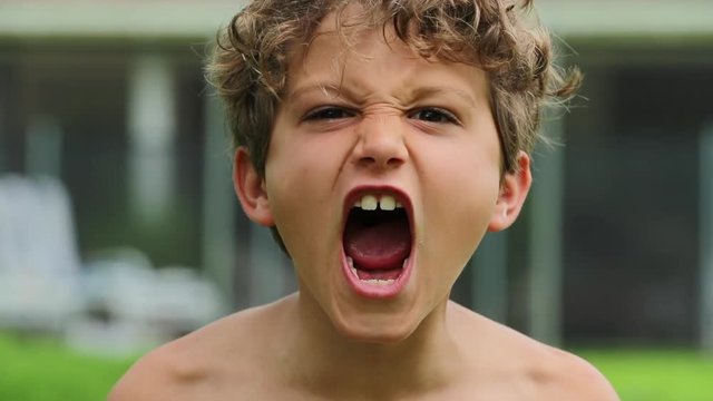 Child boy screaming from top of his lungs in slow-motion 120fps. Kid yelling roaring to camera