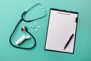 Stethoscope in doctors desk with tablet, pen, inhaler and pills