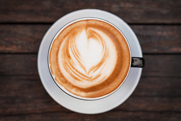 A close-up of cup of coffee on a dark wooden table.