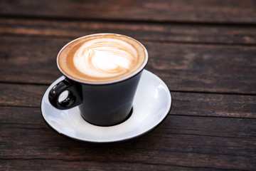 A cup of coffee on a dark wooden table.