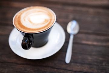 A cup of coffee on a dark wooden table.