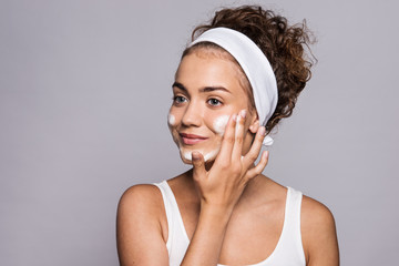 Portrait of a young woman cleaning face in a studio, beauty and skin care.