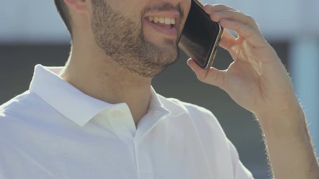 Cropped shot of smiling young man talking on phone. Smiling handsome man talking with interlocutor through smartphone. Communication and technology concept