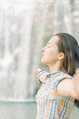 Young woman relaxing on background of waterfall.