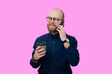 Portrait of handsome businessman talking on phone and holding his coffee