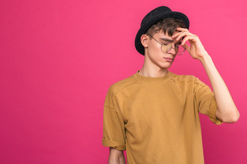 Portrait of thoughtful young guy in black hat on pink background