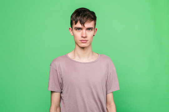 Portrait of a young guy in casual clothes standing on a green background