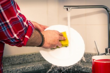 man hand washing dishes over the sink in the kitchen