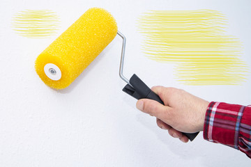 painting with roller the wall of yellow, concept of decoration and renovation