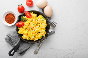 Scrambled eggs on skillet over gray stone background.